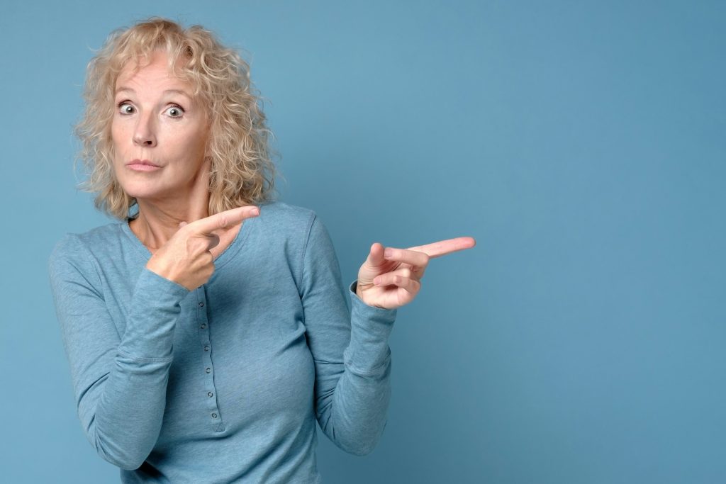 Cheerful woman looking aside pointing. Pay attention to this information.