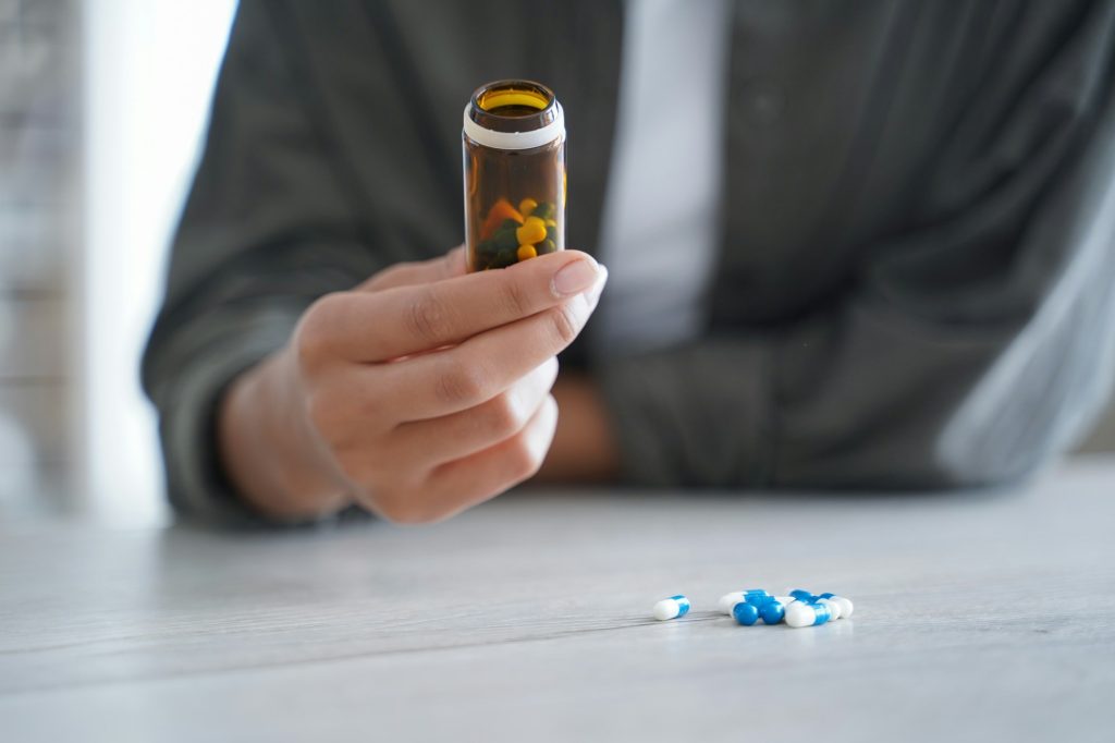 Closeup woman hold pills bottle of nutritional dietary supplements or medicine. Healthcare, wellness