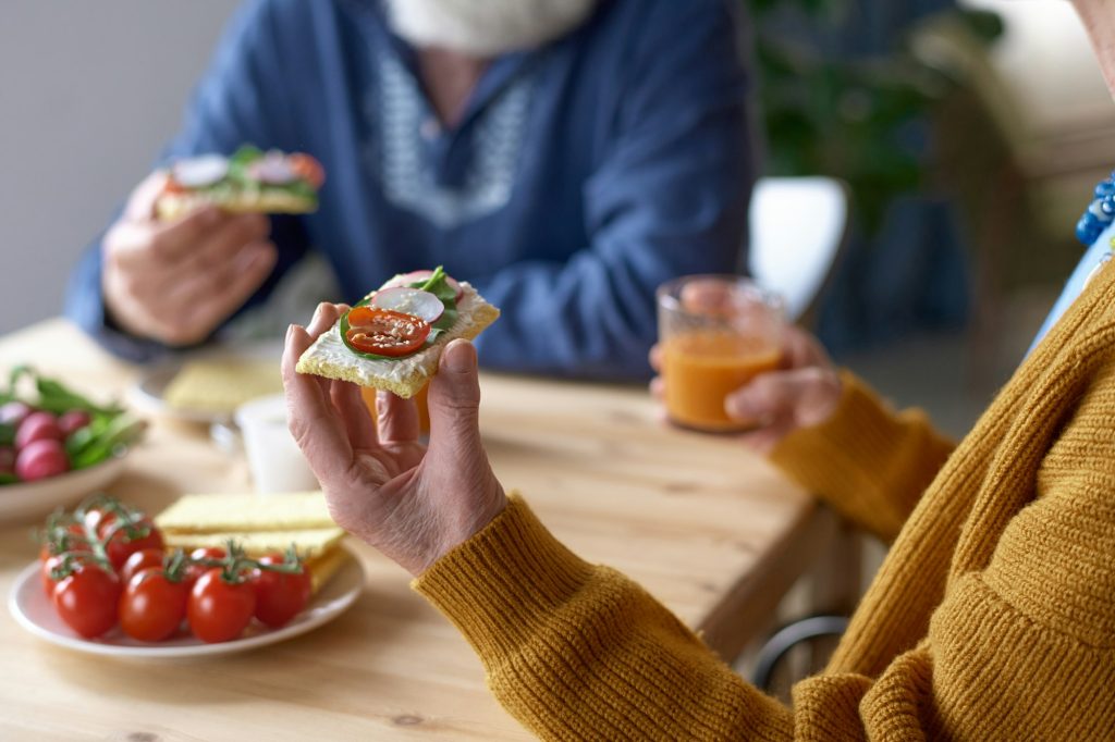 Senior woman eating sandwich for breakfast