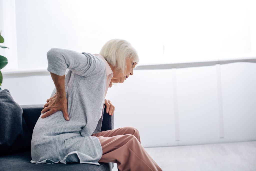 side view of senior woman having back pain in apartment