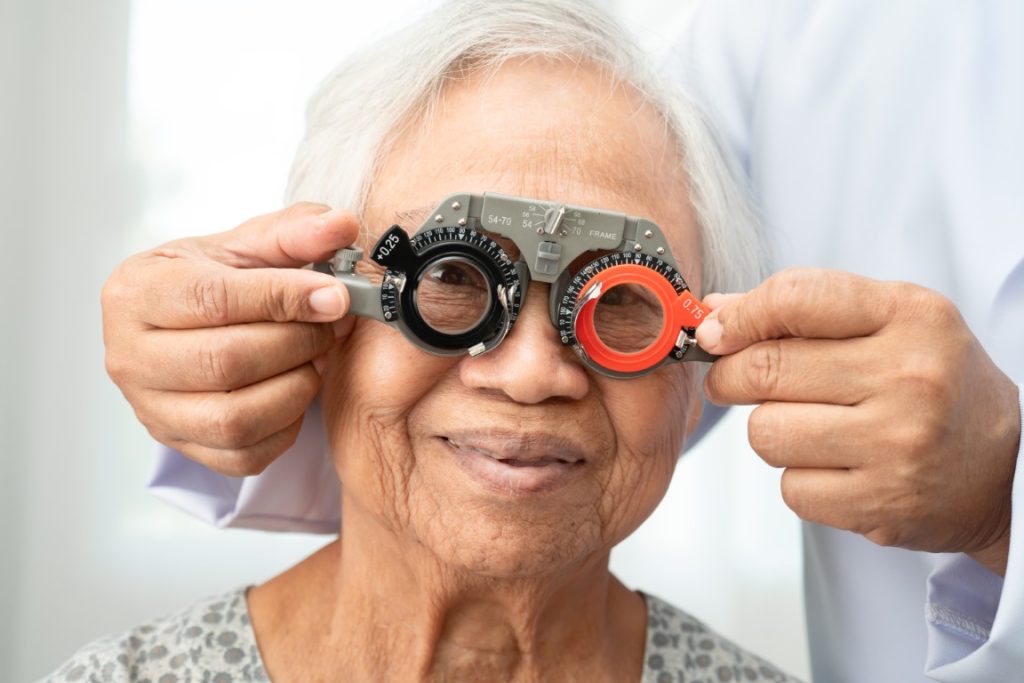 Asian senior woman wearing ophthalmic vision eye test and using optical trial frame.