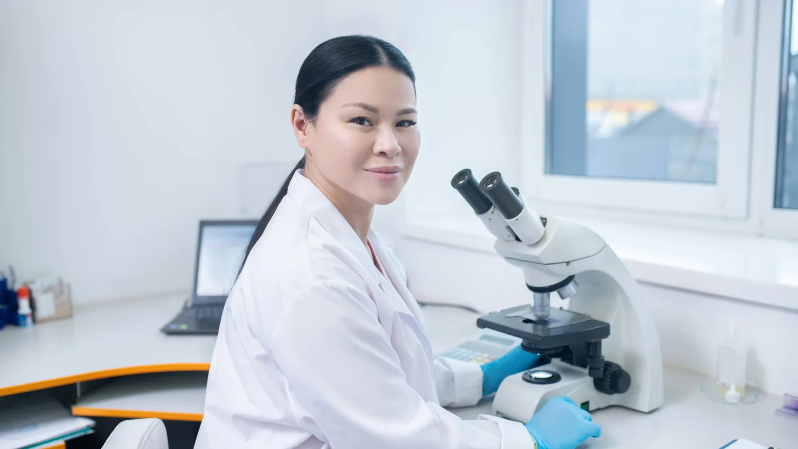 Análisis de Sangre en Tamarac: Qué Exámenes Necesita Cada Año Después de los 60 1 Especialista de laboratorio con bata blanca revisa muestras en un microscopio dentro de un laboratorio clínico
