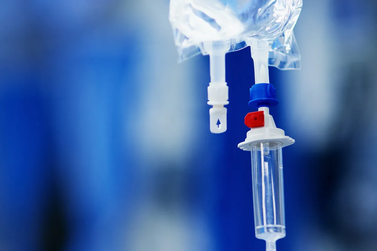 Primer plano de una bolsa de suero y la cámara de goteo de una vía intravenosa