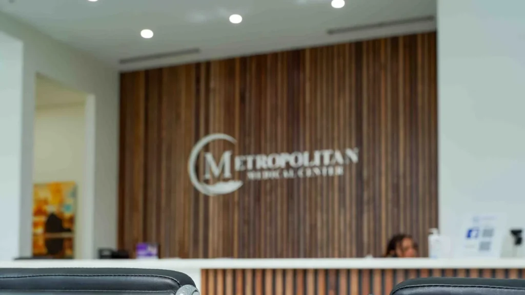 Recepción de Metropolitan Medical Centers en Tamarac, con el logo de la clínica en la pared de madera y sillas de espera
