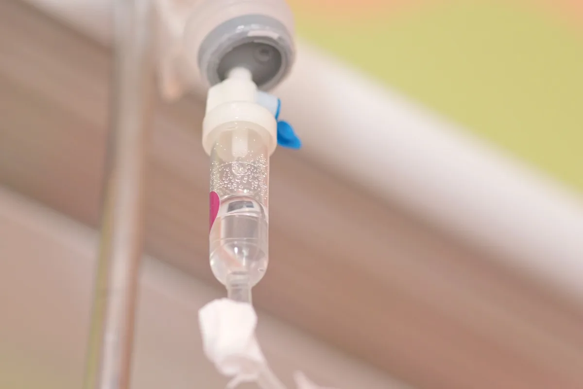 Close-up of an IV drip chamber with the infusion line in soft focus